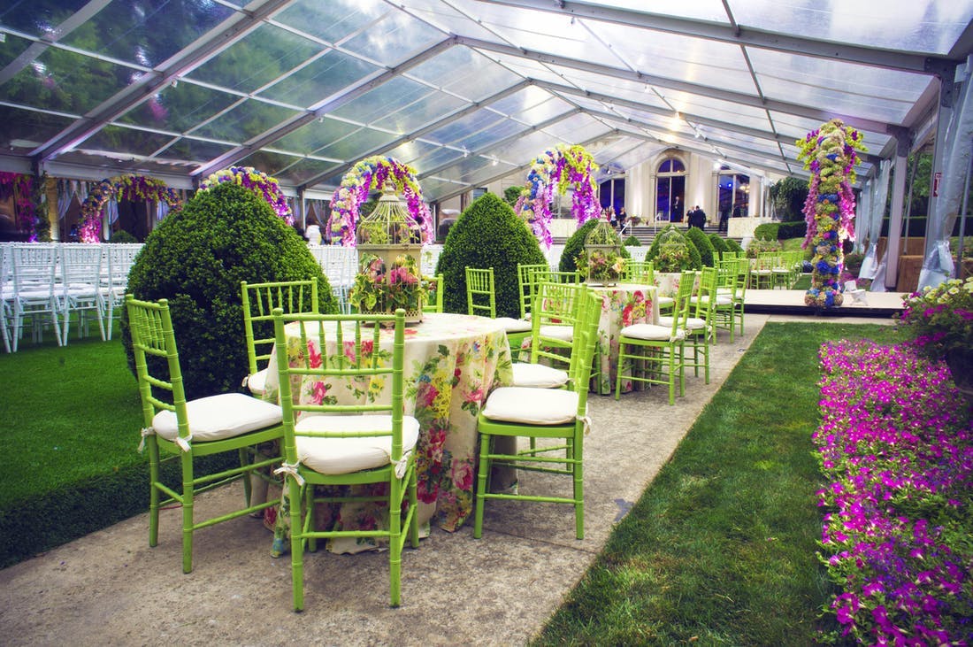 Tables and green chairs in a colorful indoor garden.
