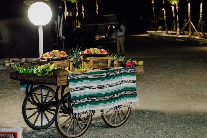 A cart with a blanket as a table cloth. Fruit in various fruit baskets sit on top.