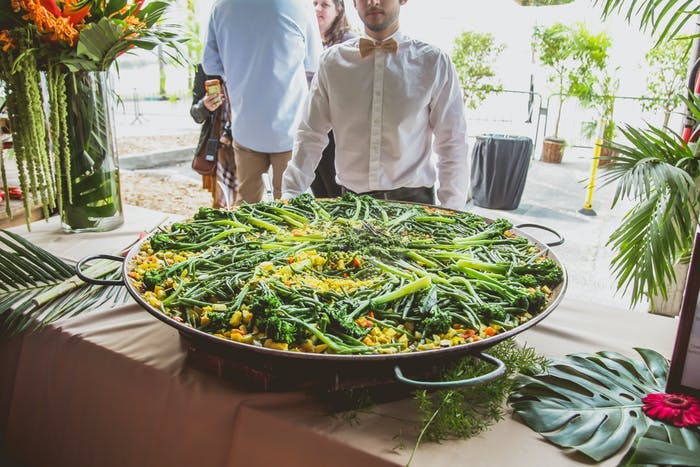 A paella with the server standing behind it