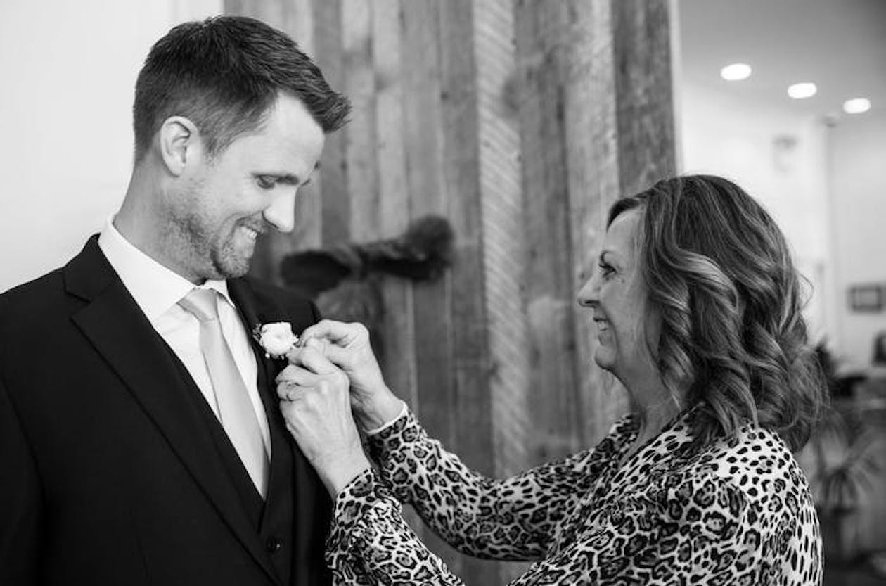 Mother pins a boutonnière to her son' tuxedo.