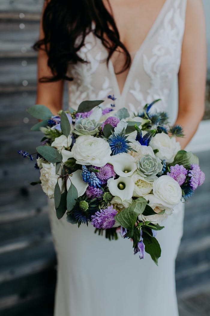Bride standing holding her bouquet full of white, purple and blue florals