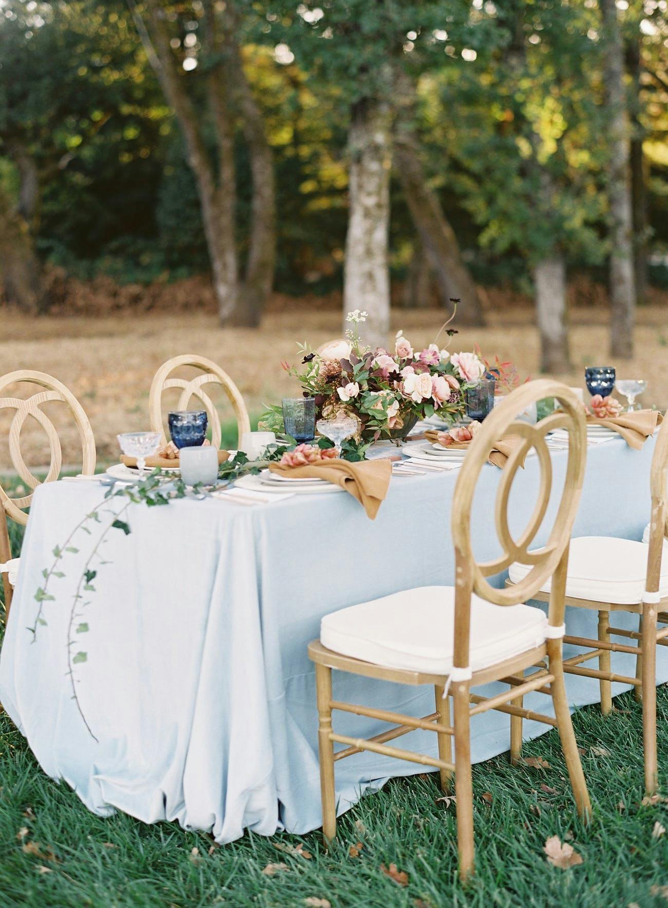 Small outdoor wedding reception table with rustic centerpieces.