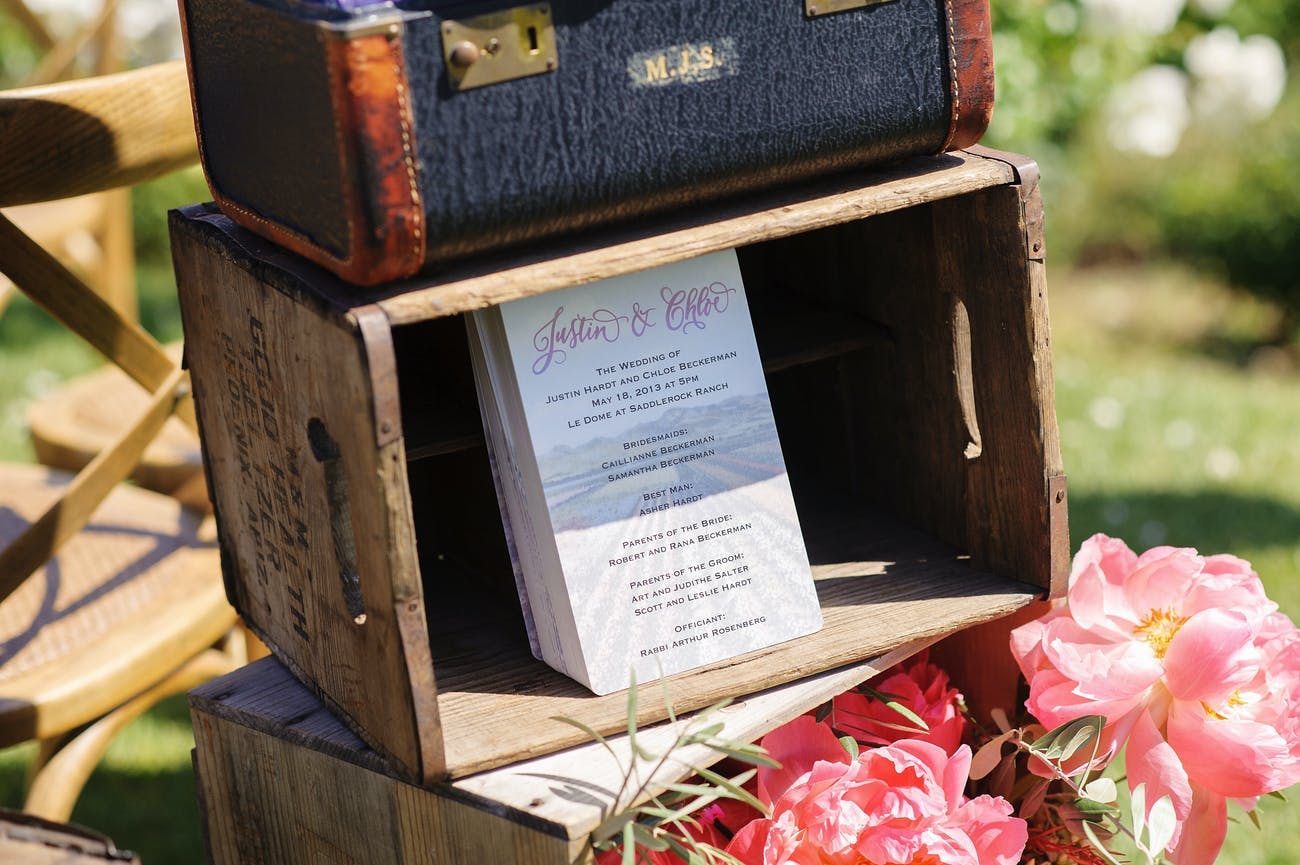 Vintage suitcases display wedding programs at this rustic wedding | PartySlate