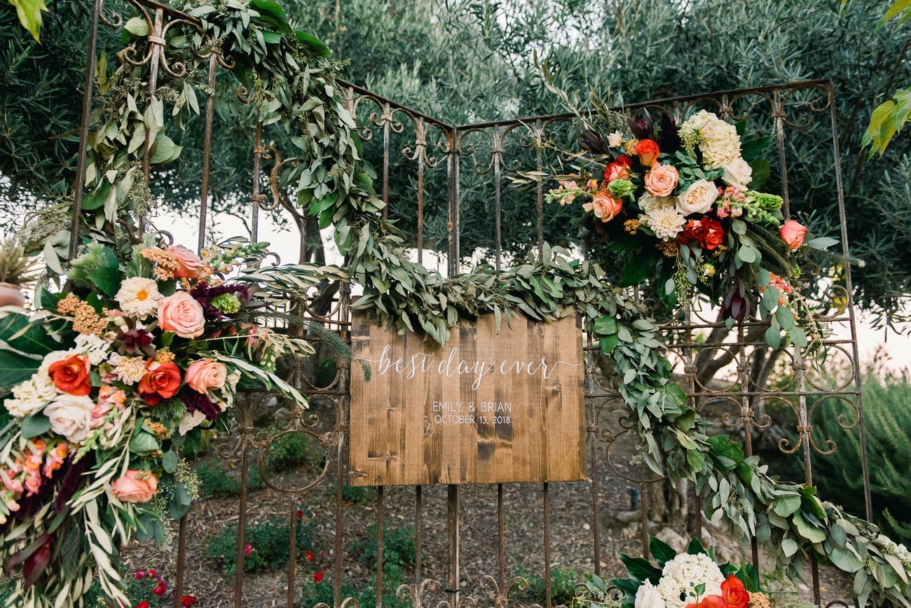 Rustic-chic wedding signage surrounded by pastel flowers | PartySlate