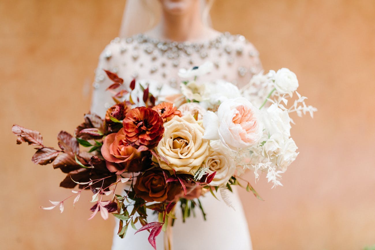 Bride stands in for photo-op of chic fall wedding bouquet | PartySlate