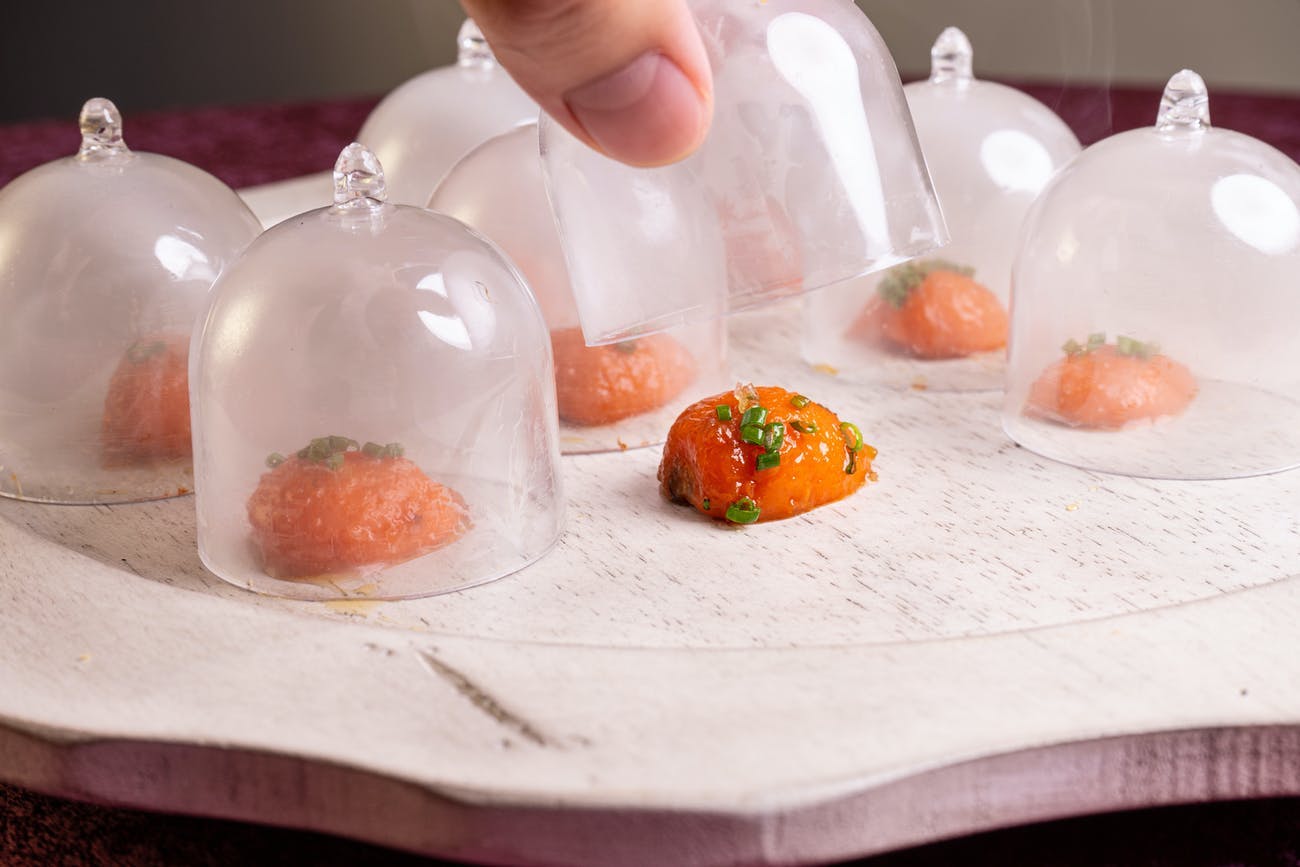 Dinner party with passed bites covered in individual glass bell coverings | PartySlate