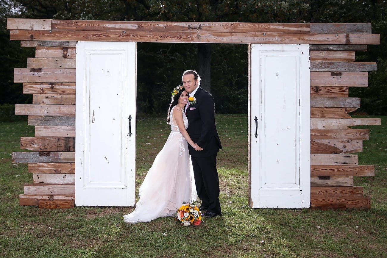 Chic-rustic wedding backdrop featuring white country doors and beams of wood | PartySlate