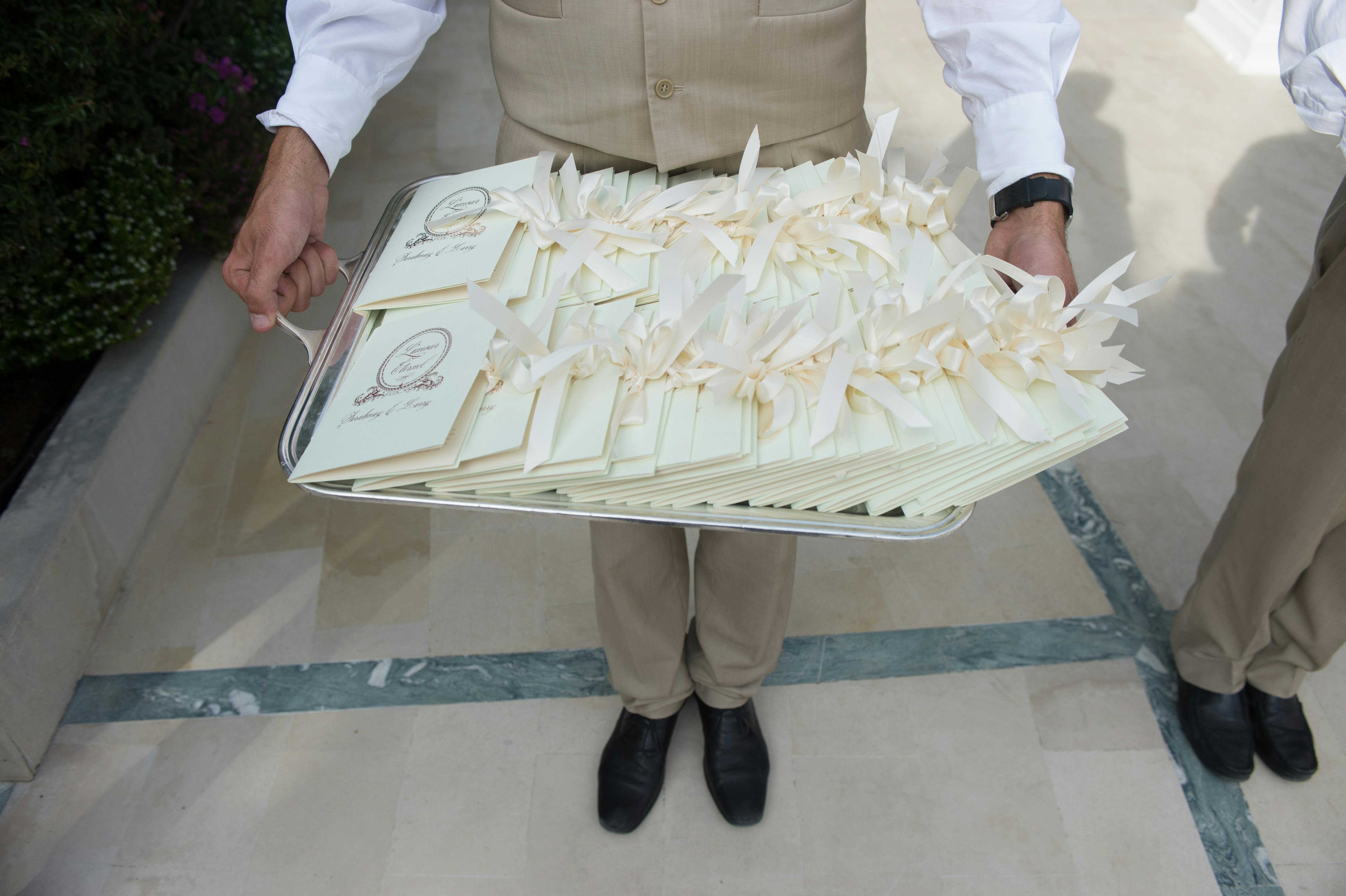 Man Carrying Wedding Programs on Silver Tray | PartySlate