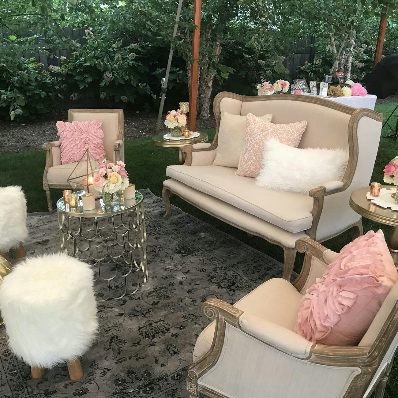 Stunning Outdoor Lounge Area with White Couches, Pink Pillows, and Furry Ottomans