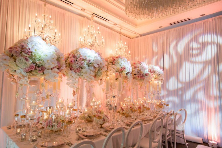 Romantic and ethereal wedding reception with tall floral centerpieces and creative light mapping.