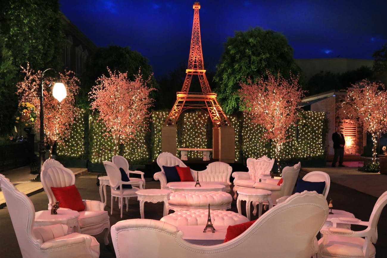 Elegant Outdoor Area with White and Pink Furniture, a Large Eiffel Tower, and Blossom Trees