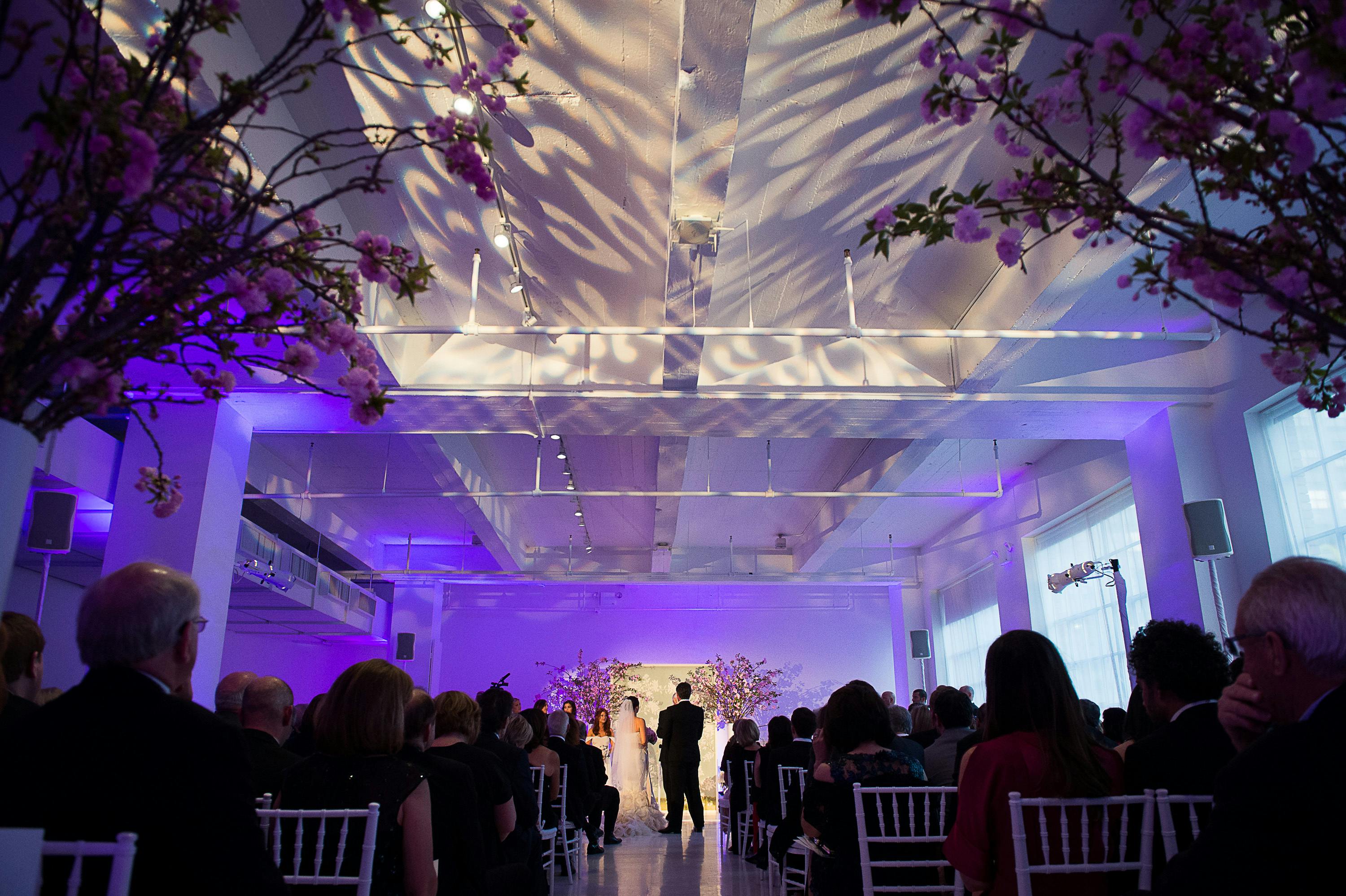 Wedding Ceremony With Shadows and Light Displayed on Ceiling Above Aisle | PartySlate