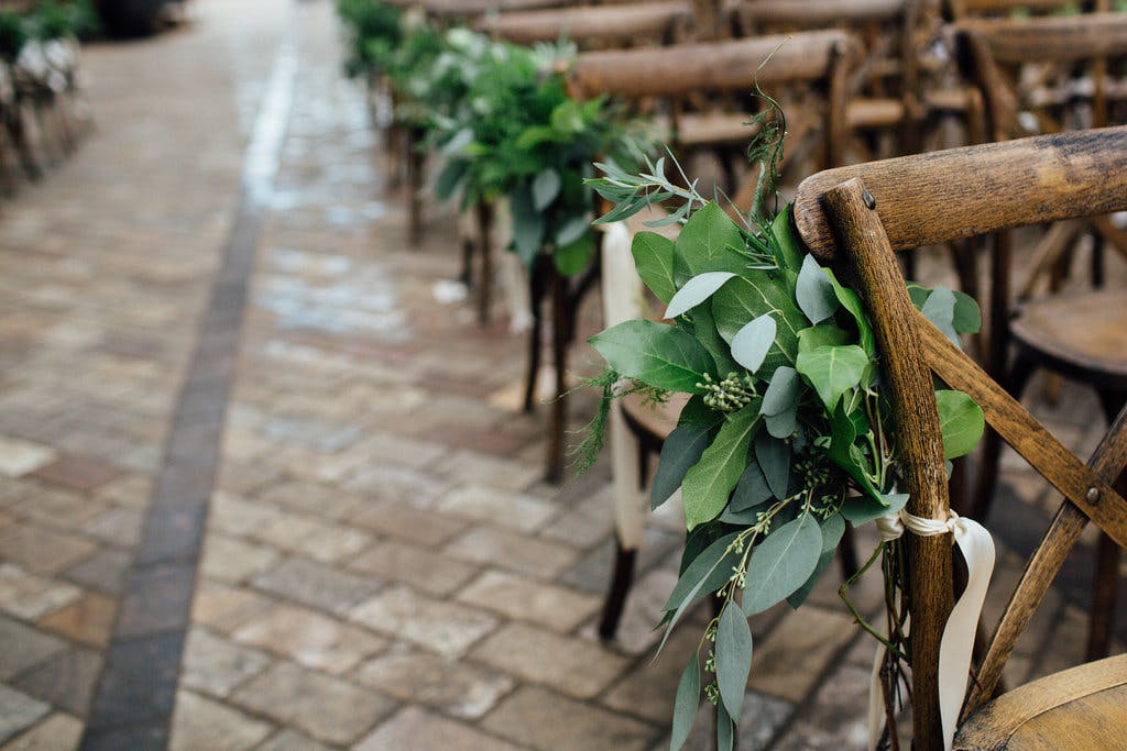 Rustic garden style wedding with wooden chairs set down the aisle | PartySlate