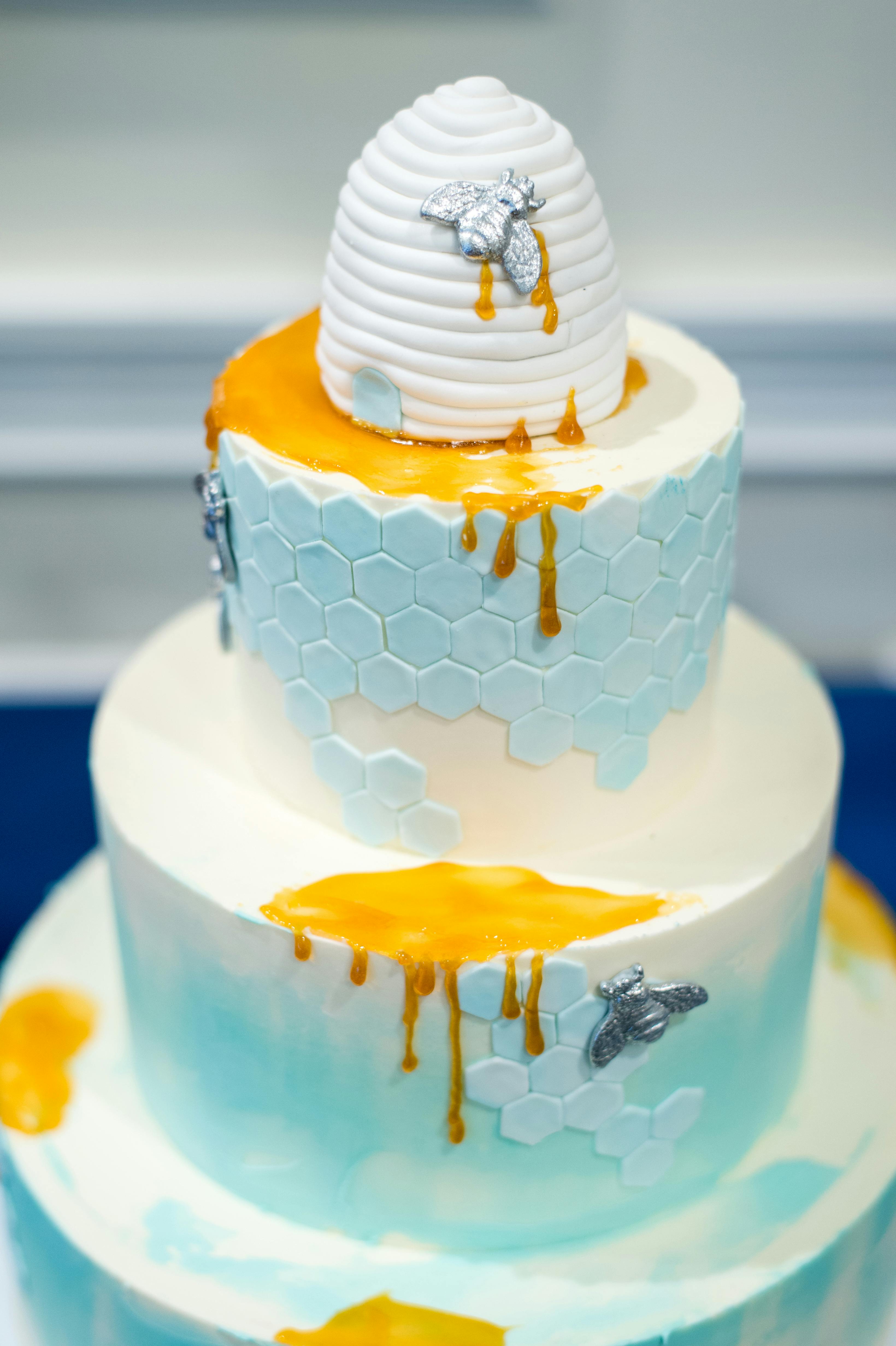 baby shower tiered cake with honeycomb details and dripping honey-like icing | PartySlate