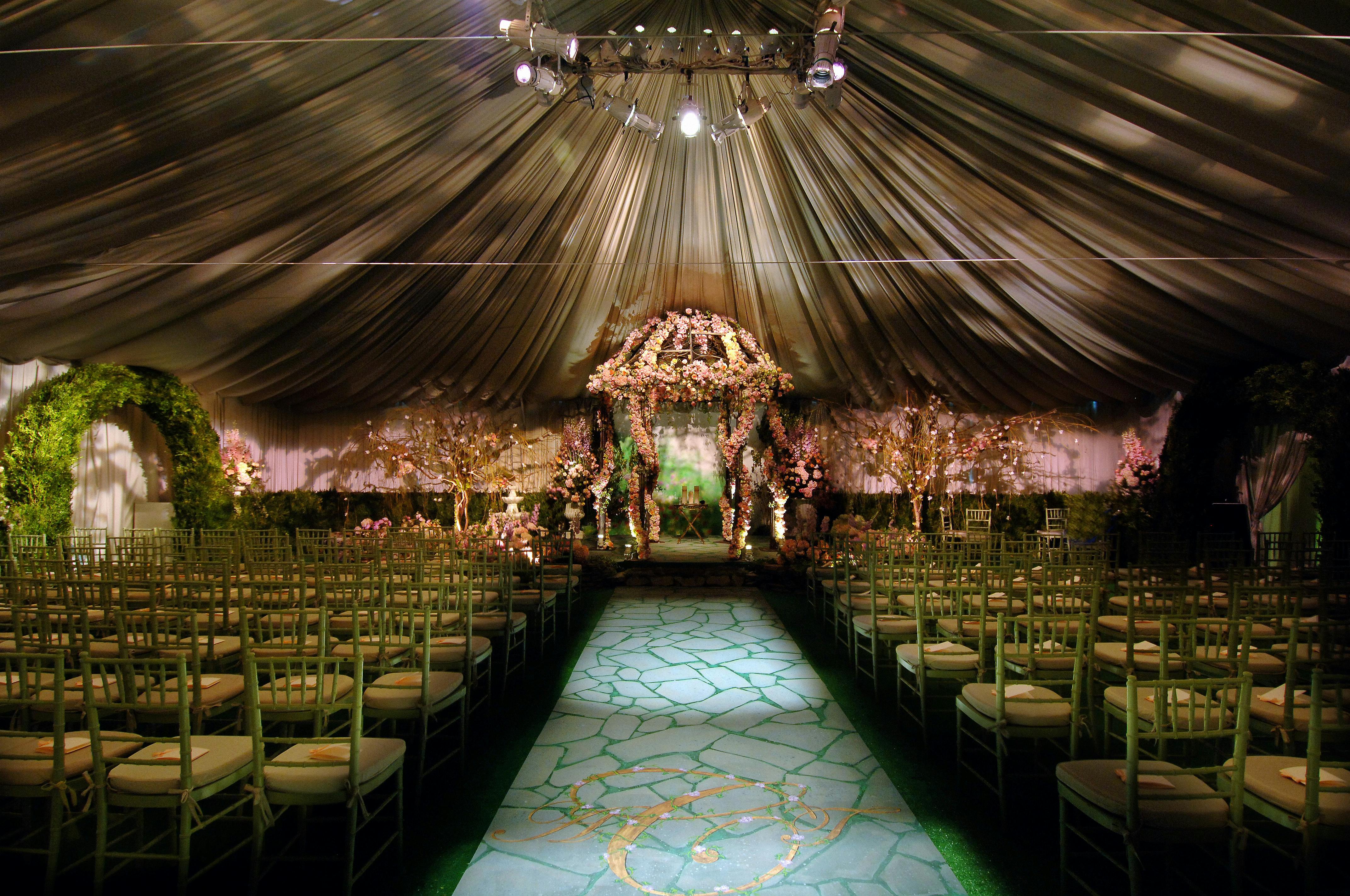 Luxurious tented wedding with evening lighting, floral and greenery decor | PartySlate