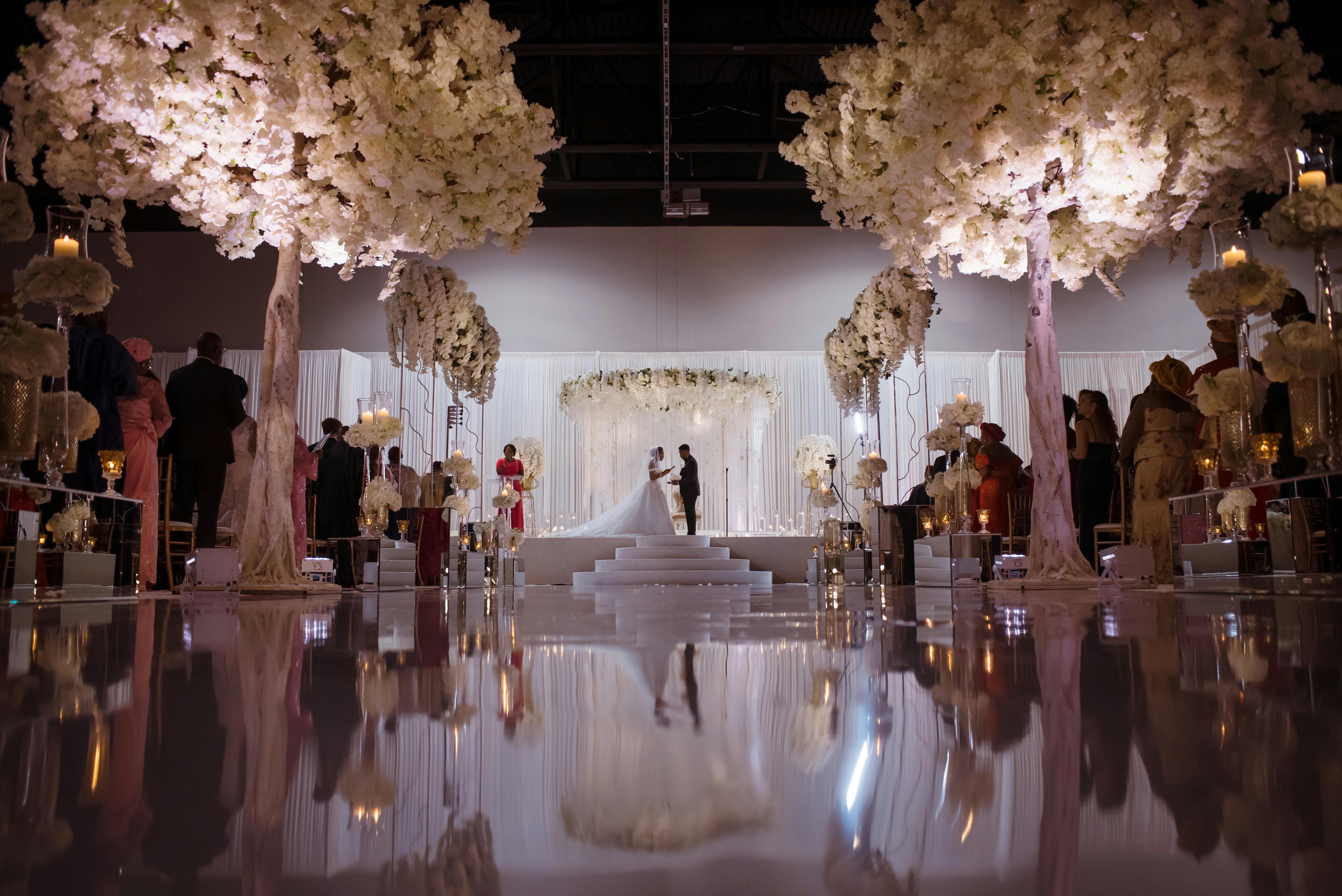 Glamorous all-white wedding with white flower trees and a mirrored aisle | PartySlate
