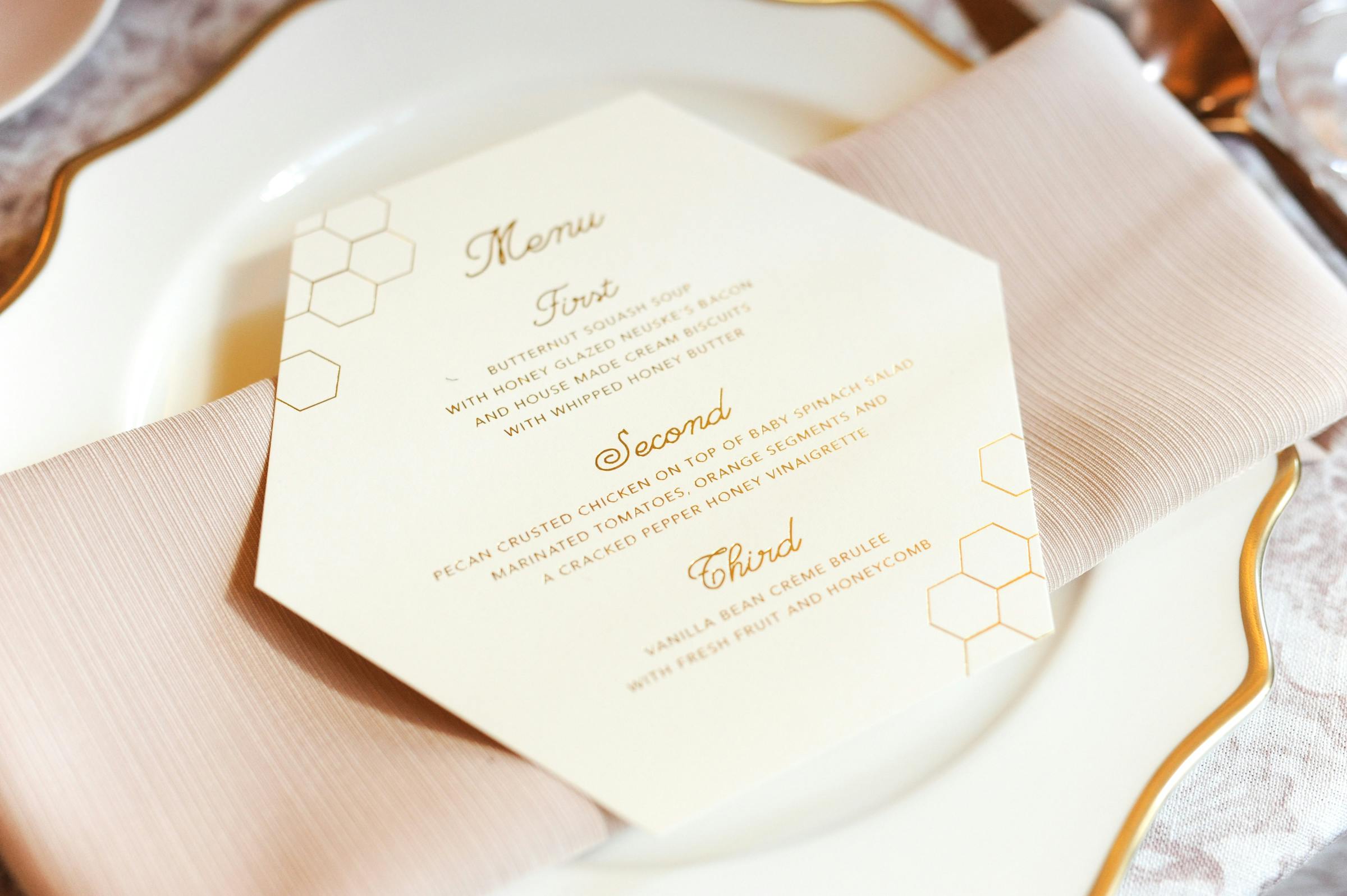 honeycomb shaped dinner menu on blush napkin at luncheon table | PartySlate