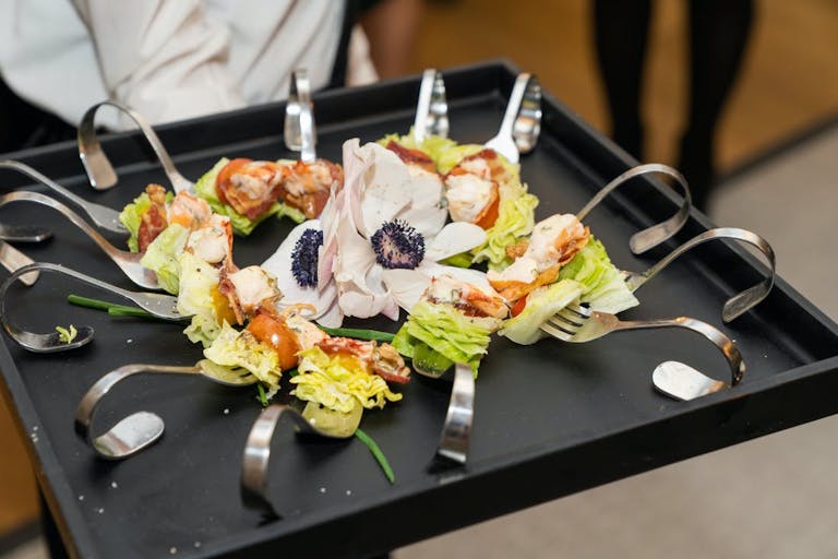 Bite size serving of salad with unique looking fork and a flower in the center | PartySlate