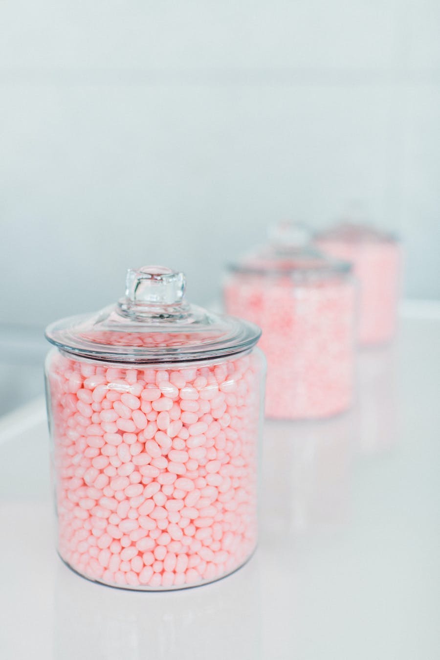 Clear canisters in a line filled with pink candy | PartySlate