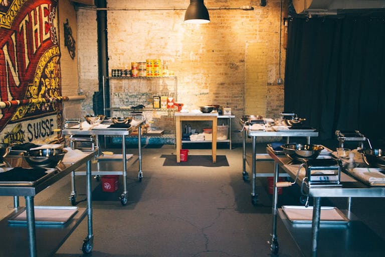 An industrial event space for a sweet 16 cooking class with five tables to cook at | PartySlate