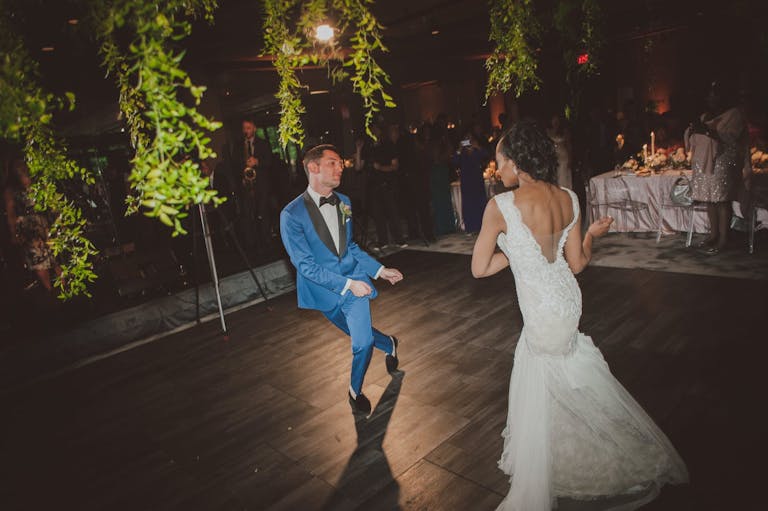 Bride and groom dancing with greenery draping down | PartySlate