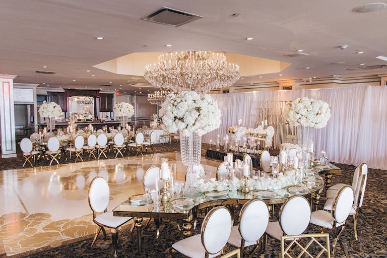 Wedding reception table arrangements with a gold dance floor and white florals | PartySlate