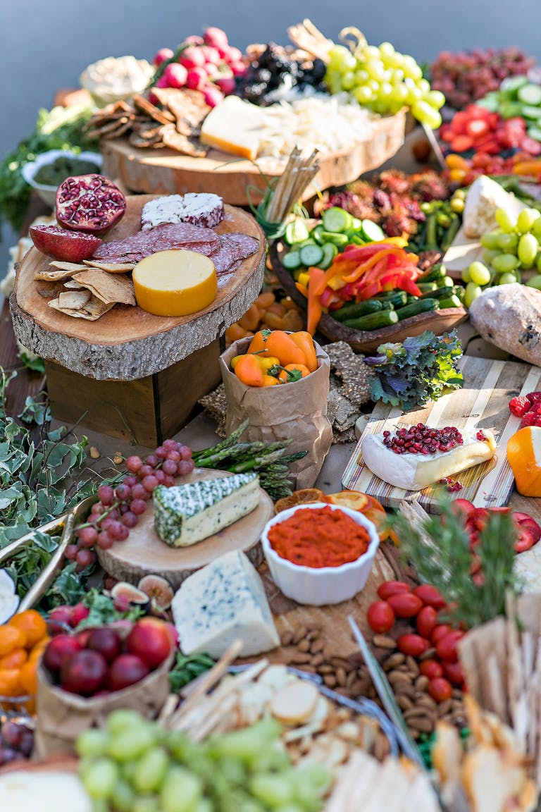 A table covered with wooden trays, piled high with meats, cheese, vegetables, and fruit | PartySlate