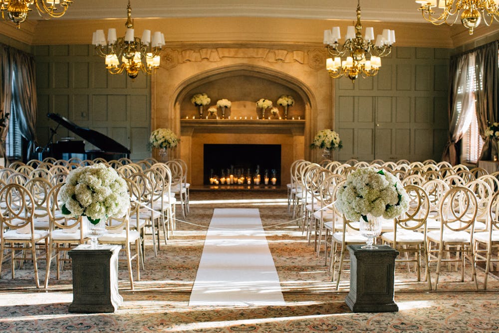 Wedding Ceremony Site with White Hydrangea Aisle Markers and Fireplace Backdrop