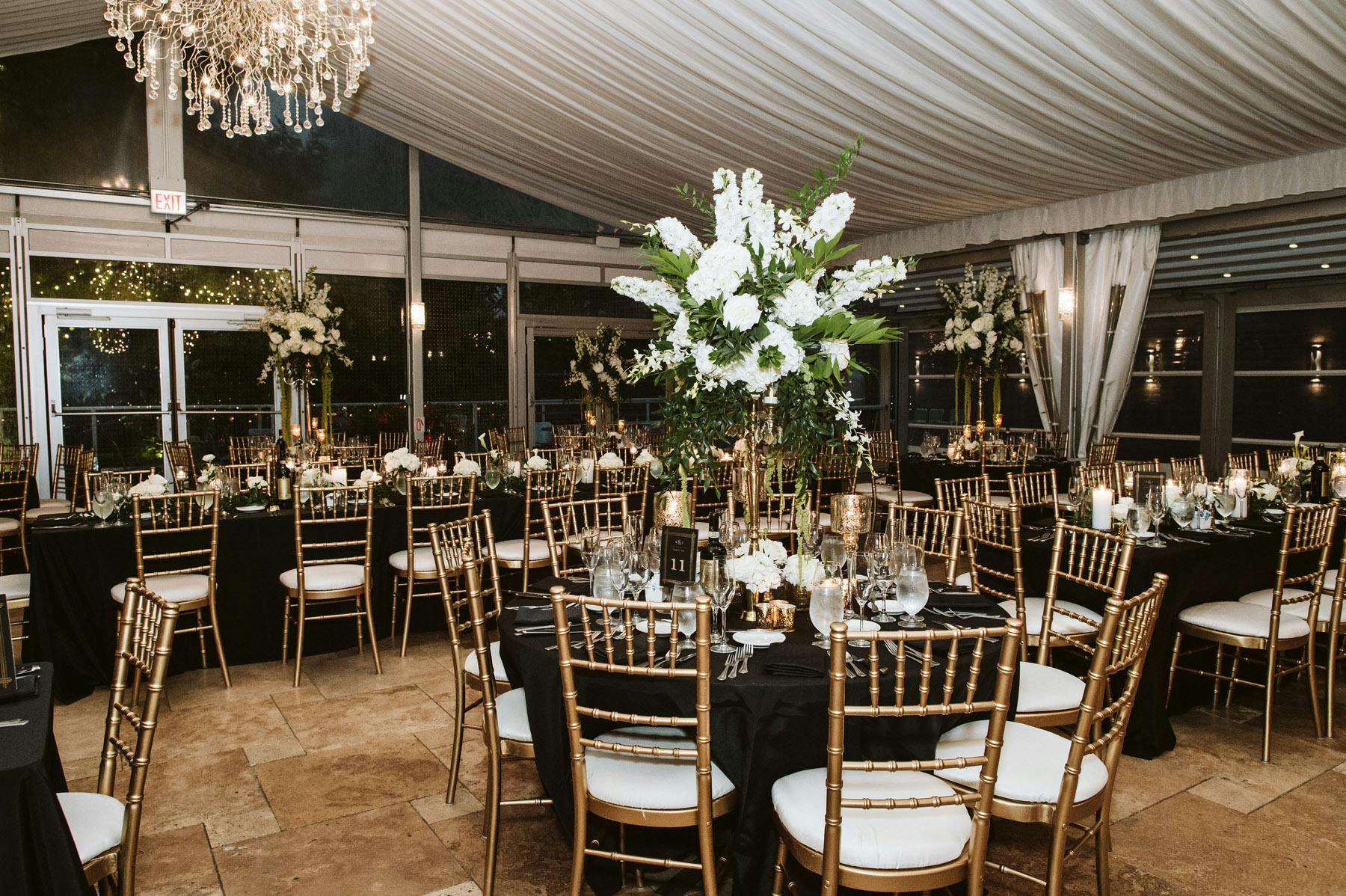 Tented Wedding Reception Venue with Gold Chavari Chairs, Black Linen, and Towering Sputnik-Style Hydrangea Wedding Centerpiece With Greens and Orchids