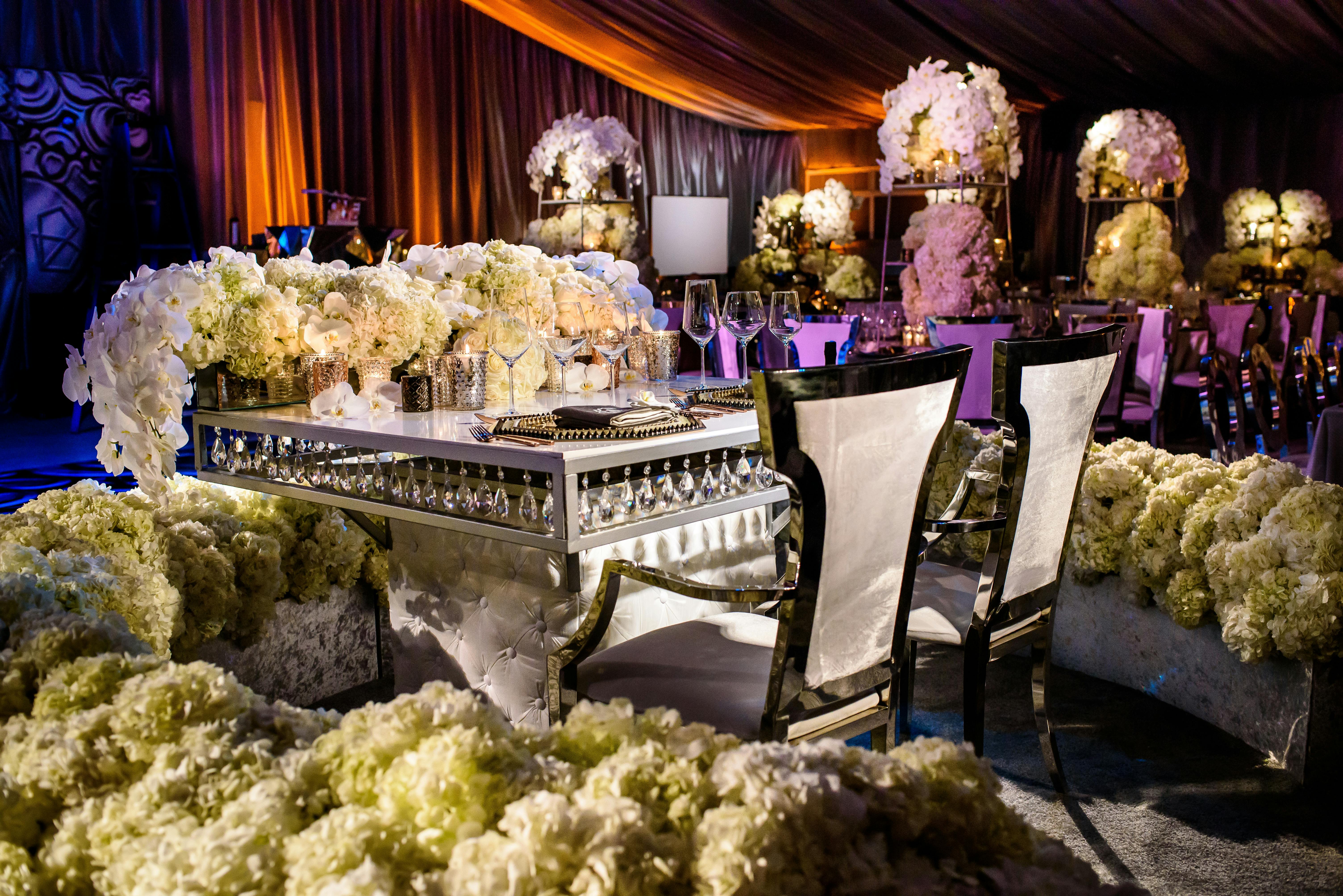 Sweetheart Table With with White Orchid and Hydrangea Wedding Centerpieces Surrounded by a Sea of White Hydrangeas