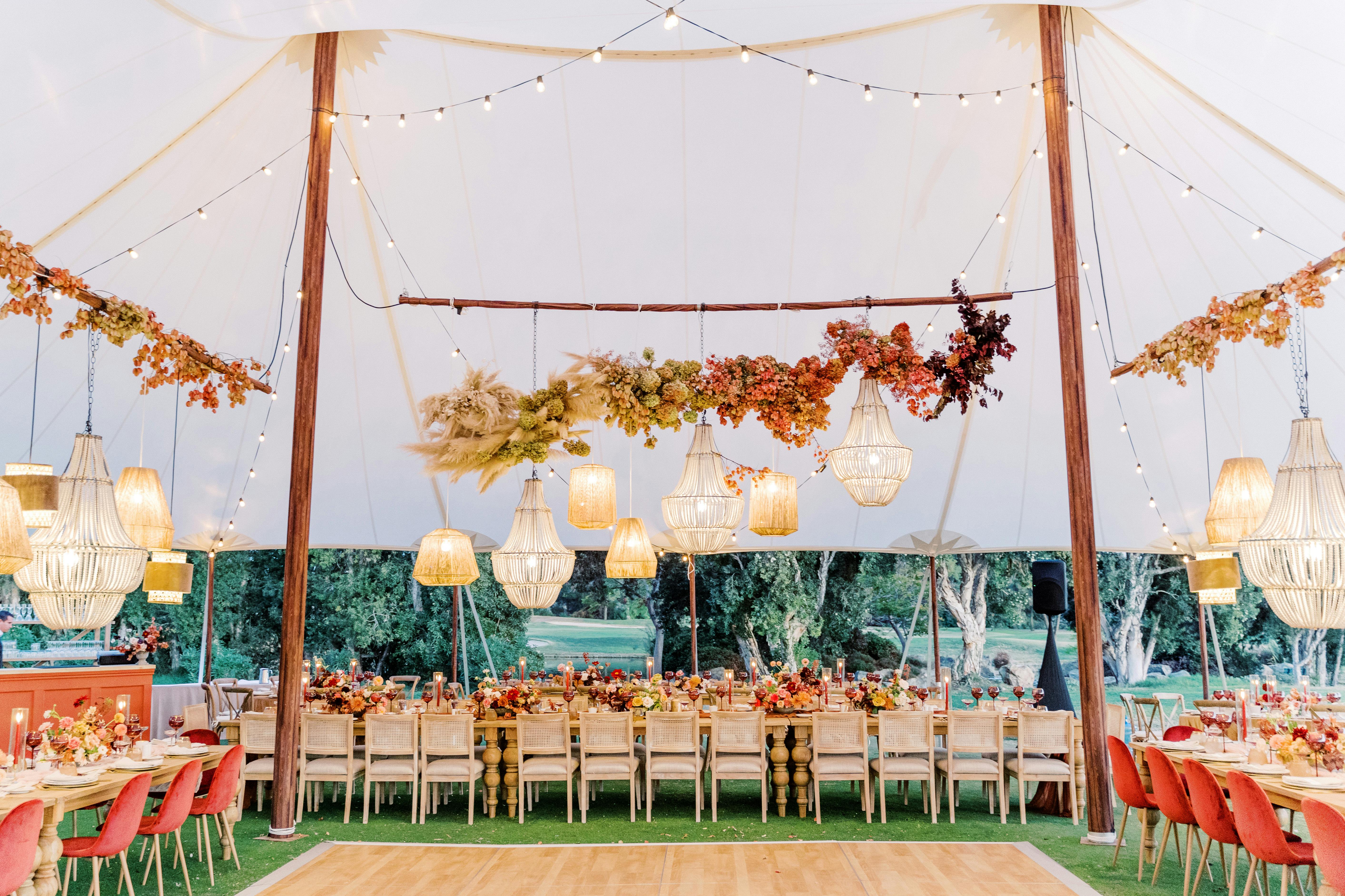 Brightly white and pink floral tented wedding reception with hanging lamp fixtures | PartySlate