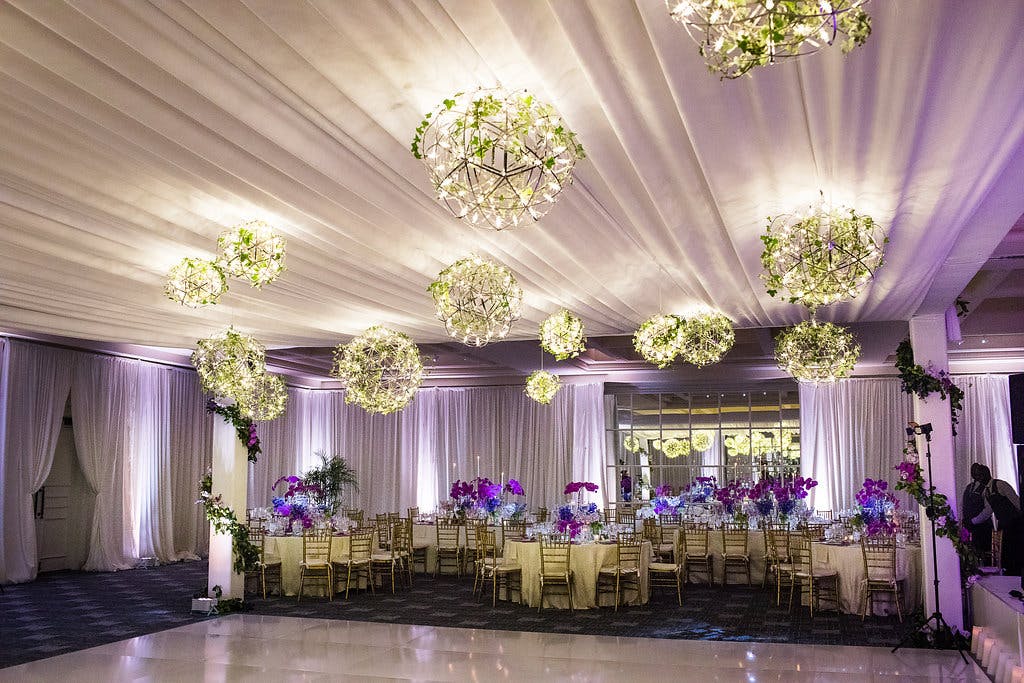 Wedding Reception With Purple Uplighting and Spring Greenery Lighting Fixtures