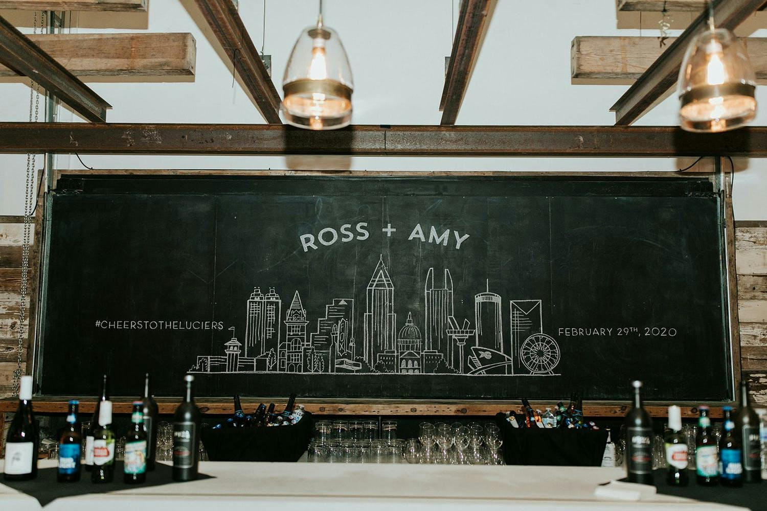Wedding With Chalkboard Signage that Features City Scape and Couples Names | PartySlate