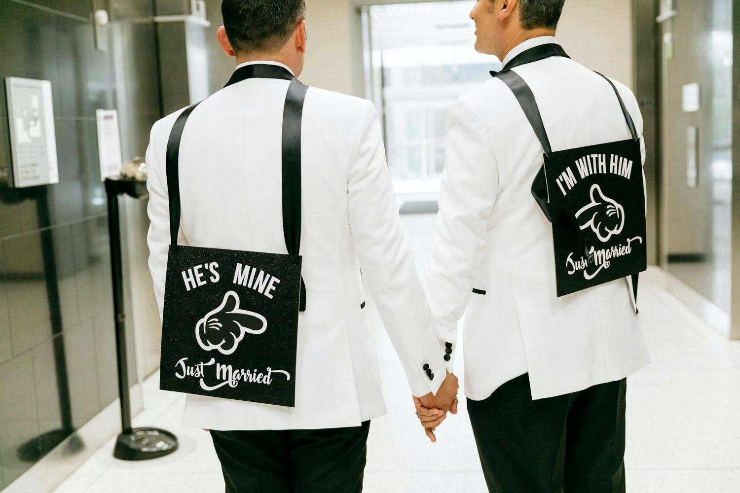 Two Grooms Wear Just Married Signs in Black and White Wedding Colors | PartySlate