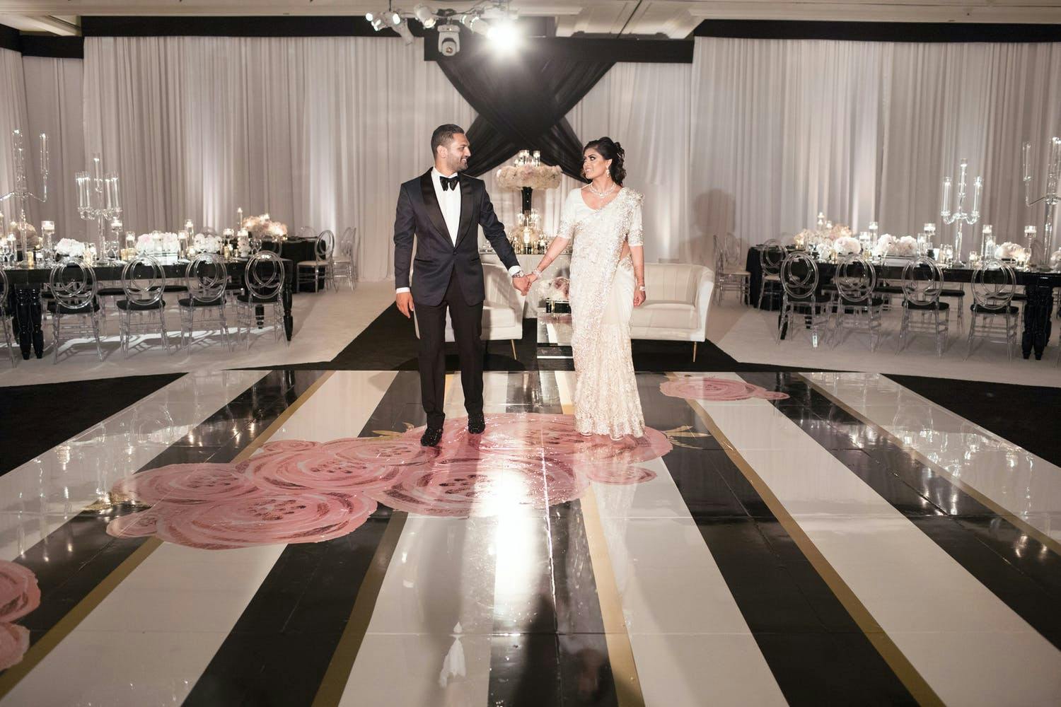 Couple Poses on Black and White Dance Floor With Pink Roses | PartySlate
