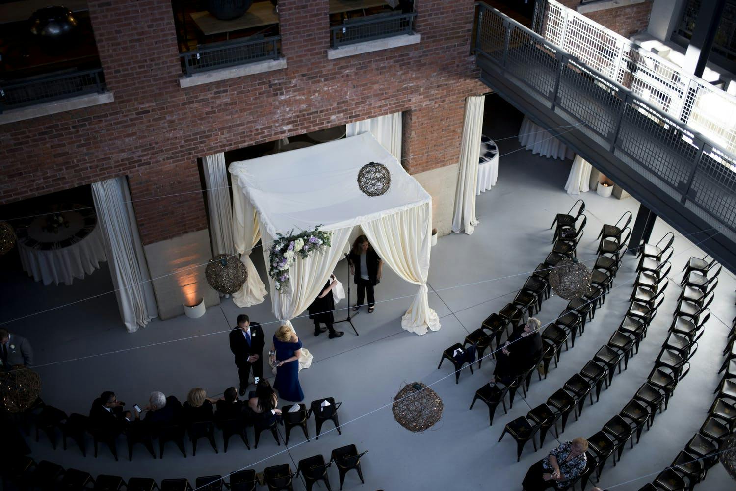 White Wedding Chuppah and Black Ceremonial Seating Against an Industrial Brick Wall | PartySlate