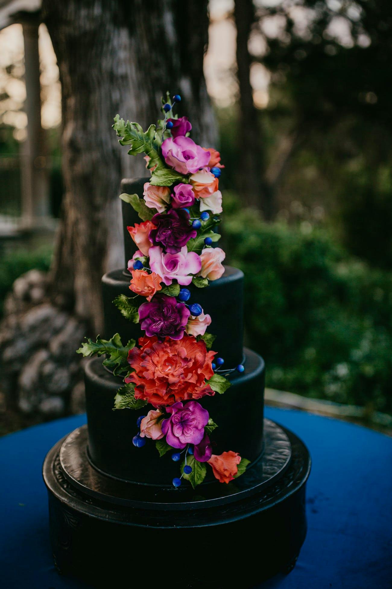 Black tiered cake with bright florals modern wedding | PartySlate