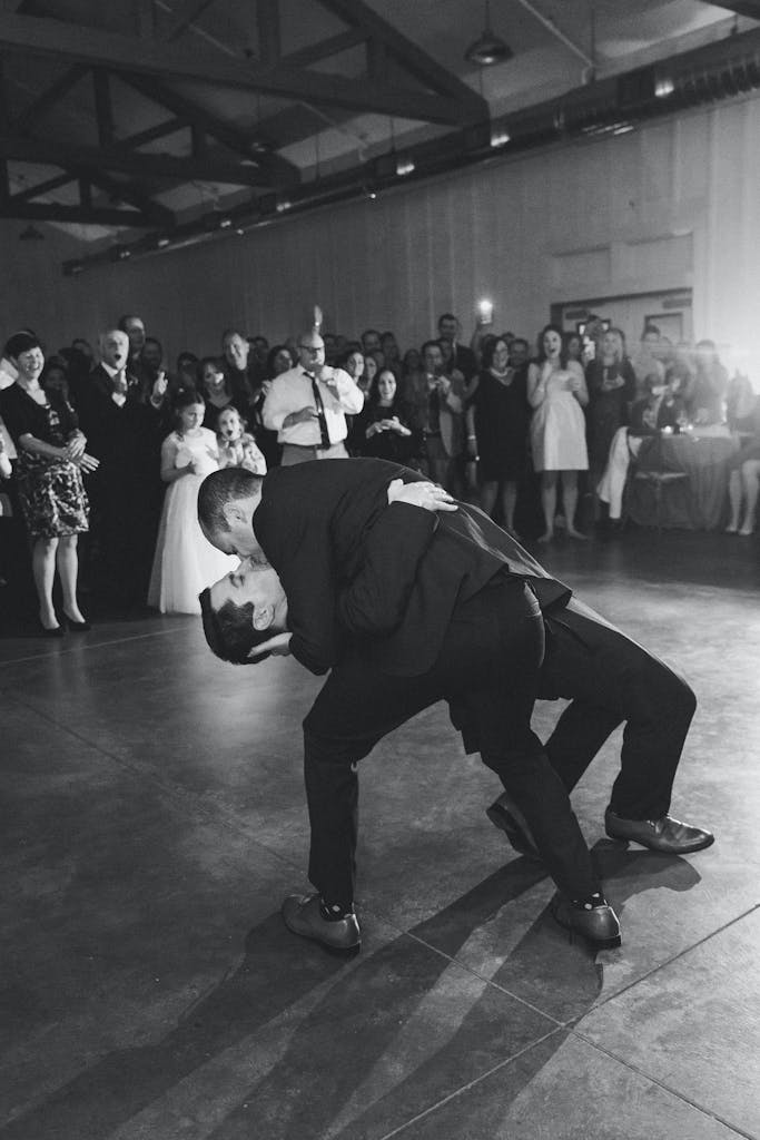 Two Grooms Kiss on Dance Floor While Surrounded by Friends | PartySlate