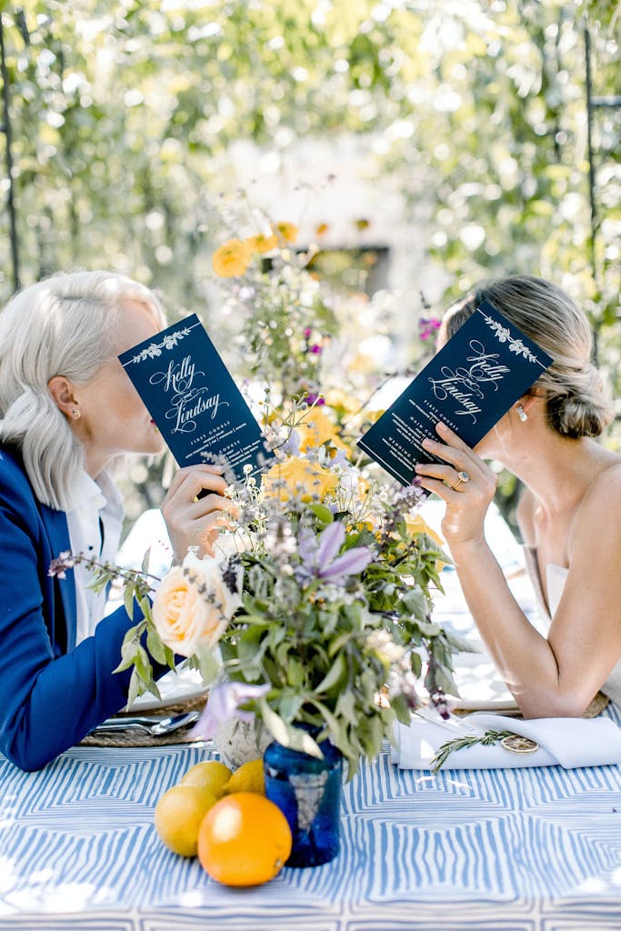 Bride and a Friend Have Private Conversation Behind Two Menus | PartySlate