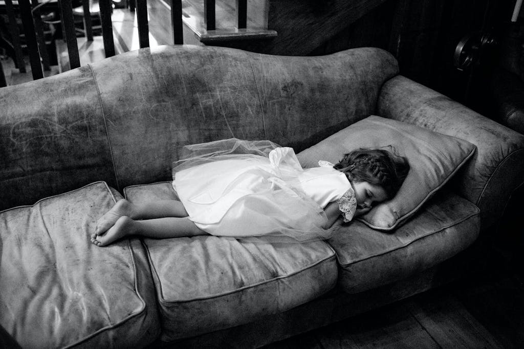Little Girl in White Party Dress Sleeps on Sofa | PartySlate
