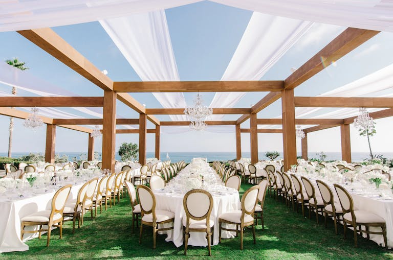 Outdoor beach wedding venue with turf and white linen draping | PartySlate