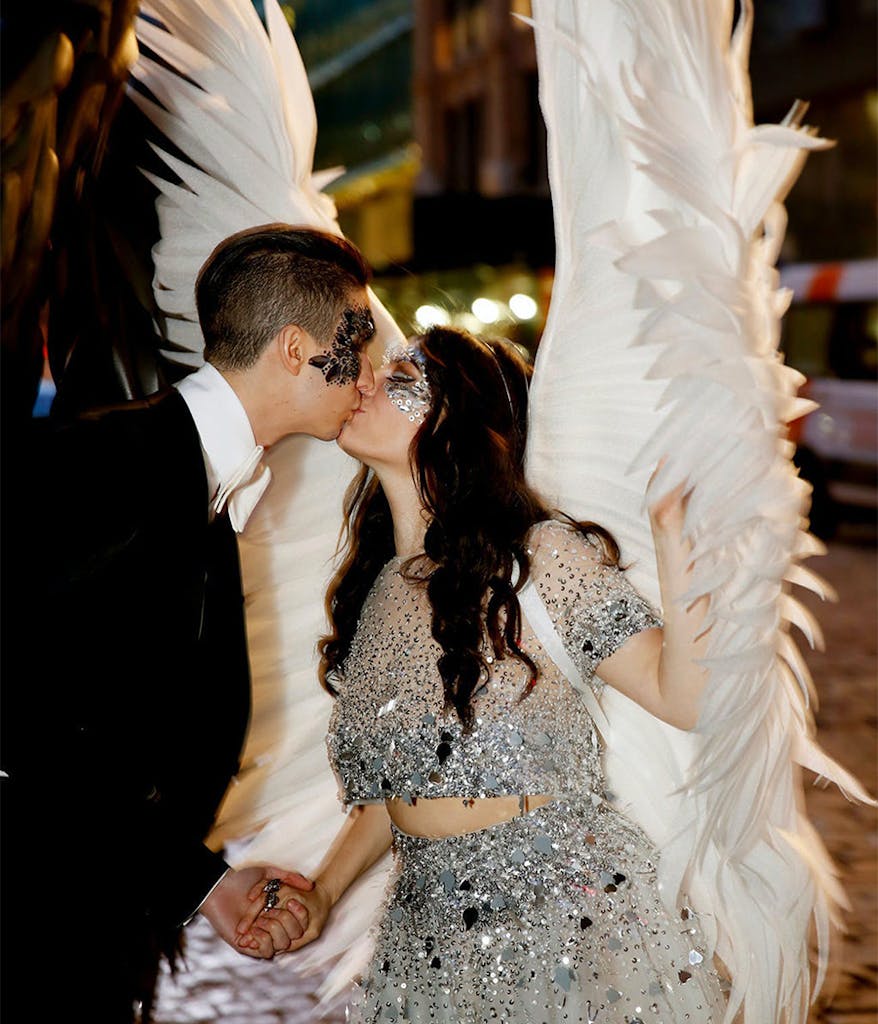 bride and groom kissing in costume at their themed wedding wearing masks and wings