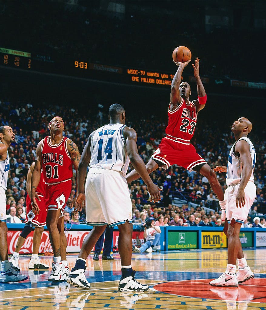 Michael Jordan in the air shooting the basketball during a game as he plays for the Chicago Bulls