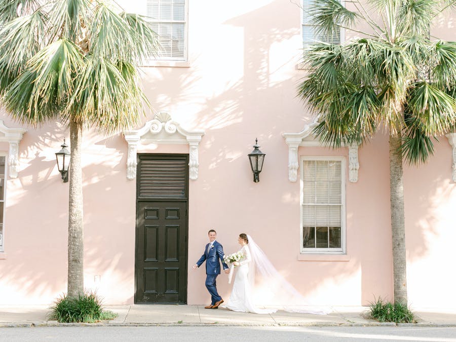 Micro wedding photo shoot with light pink wall background and palm trees | PartySlate