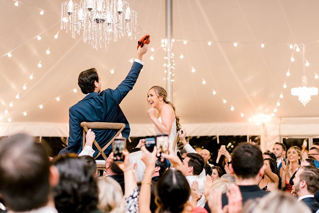 Hora in Pole Wedding Tent With String Lights and Chandeliers | PartySlate
