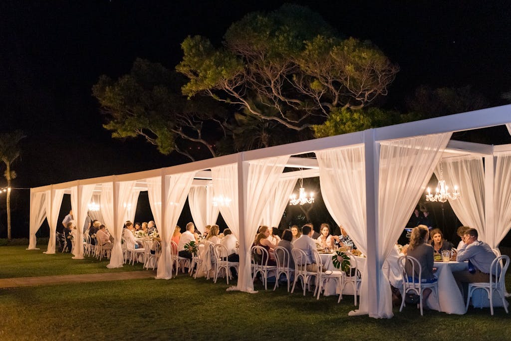 Long Cabana Wedding Tent With White Drapery Illuminated by Chandeliers | PartySlate