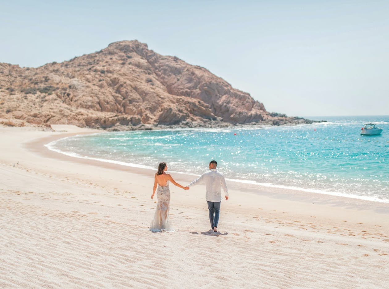 Beachside wedding with a bright blue ocean and mountains | PartySlate