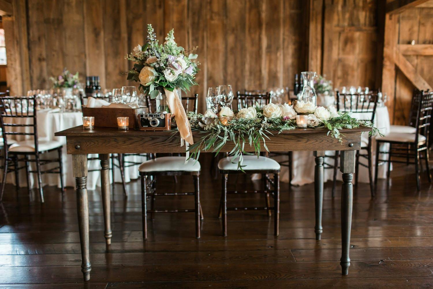 Rustic Wedding Centerpieces With Greenery, Peach Ribbon, and a Vintage Camera | PartySlate