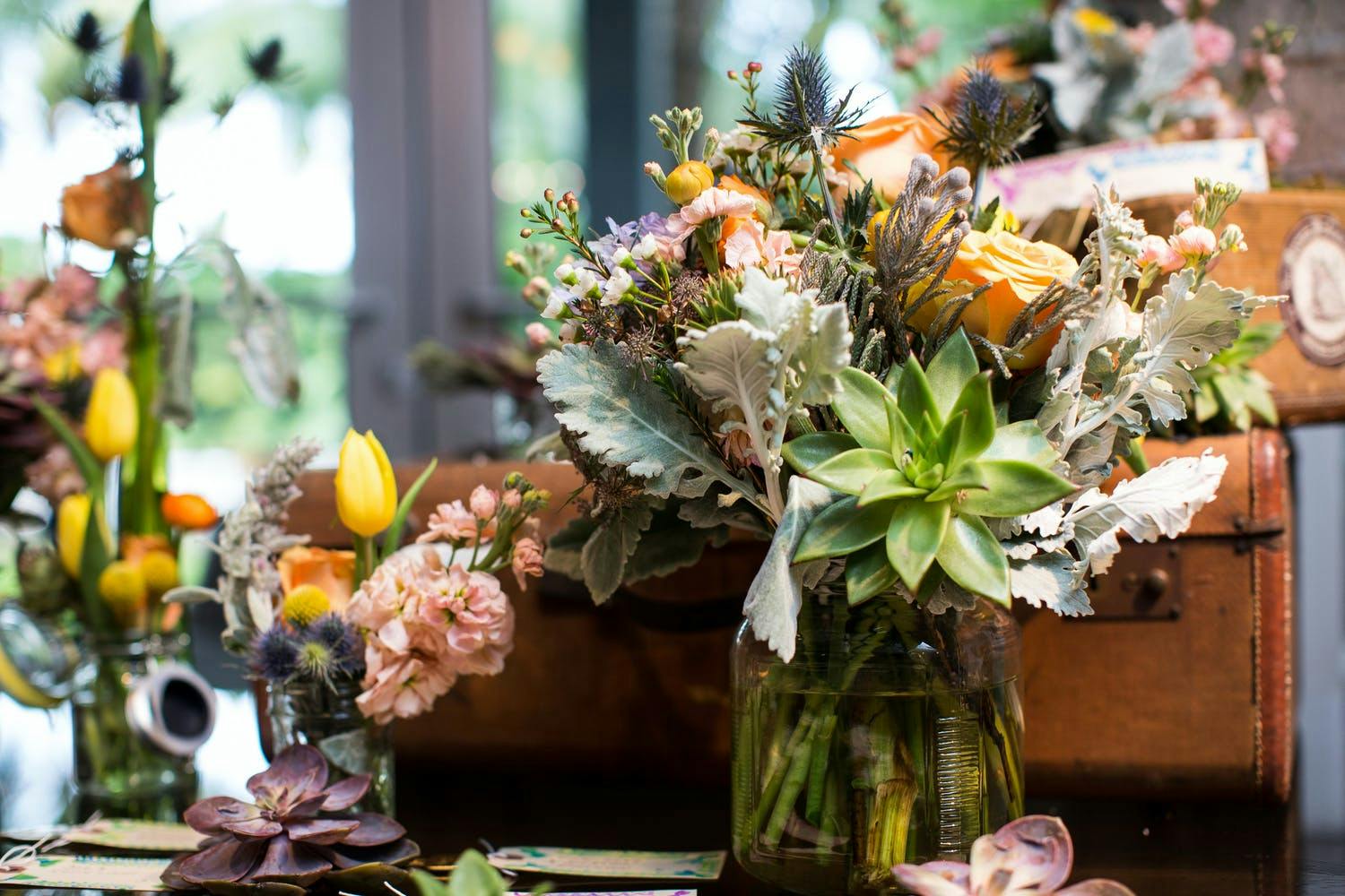 Bright Floral Wedding Centerpieces With Succulents and Rustic Suitcases | PartySlate
