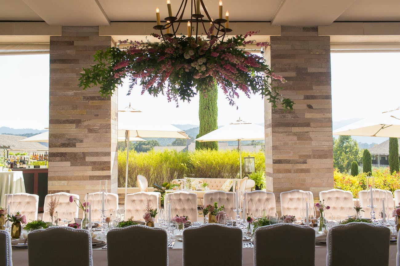 Sophisticated micro wedding with floral arrangement hanging above the dining table | PartySlate